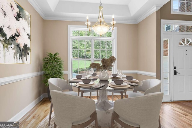 dining space with light wood finished floors, baseboards, a raised ceiling, and an inviting chandelier