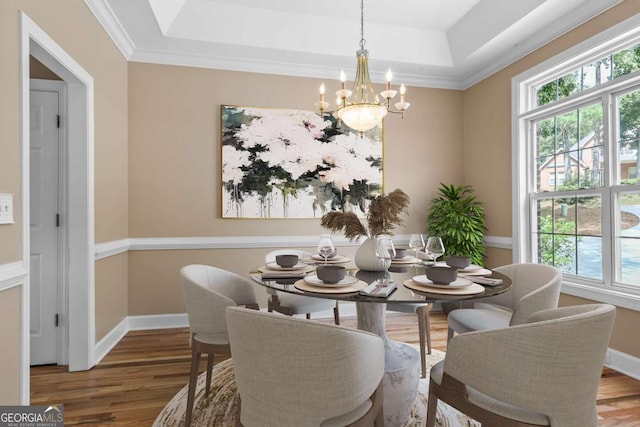 dining room with an inviting chandelier, a tray ceiling, wood finished floors, and baseboards