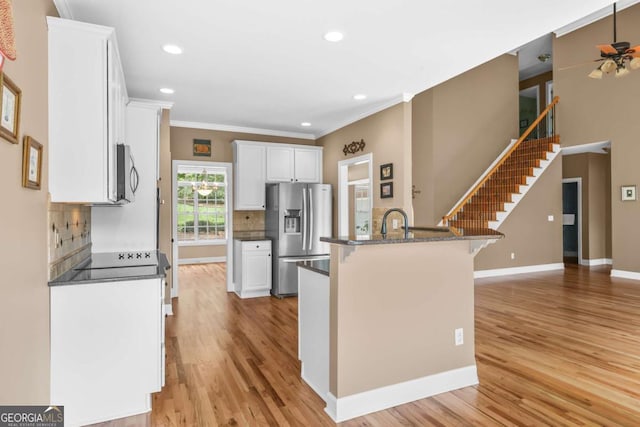 kitchen featuring light wood finished floors, white cabinetry, appliances with stainless steel finishes, and a breakfast bar area