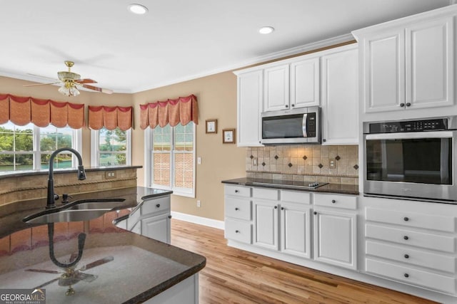 kitchen featuring backsplash, light wood-style floors, plenty of natural light, stainless steel appliances, and a sink