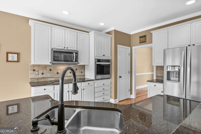 kitchen with a sink, decorative backsplash, white cabinets, appliances with stainless steel finishes, and crown molding