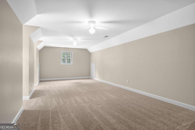 additional living space with a ceiling fan, visible vents, baseboards, vaulted ceiling, and light carpet