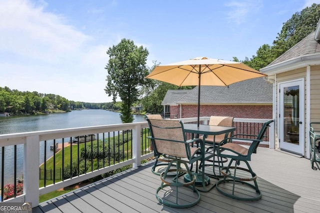 wooden deck with a water view and outdoor dining space