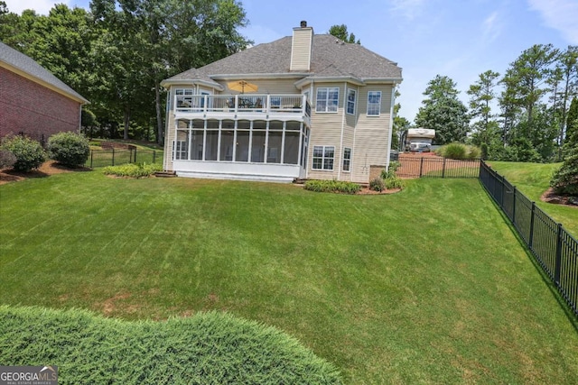 back of property with a balcony, a lawn, a fenced backyard, and a sunroom