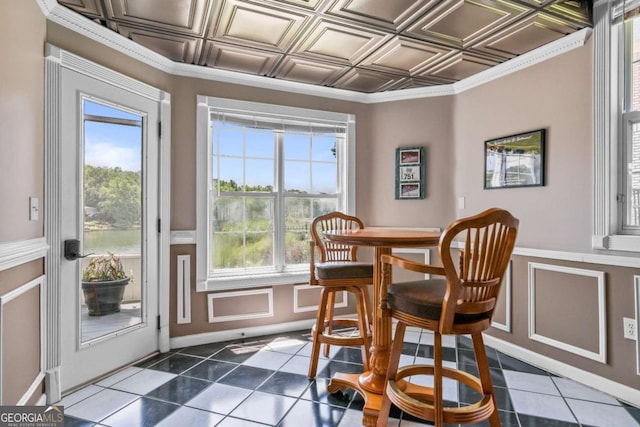 dining area with crown molding, dark tile patterned floors, a wainscoted wall, and an ornate ceiling