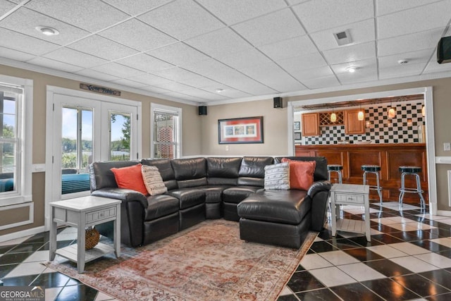 tiled living area featuring a drop ceiling, french doors, and crown molding