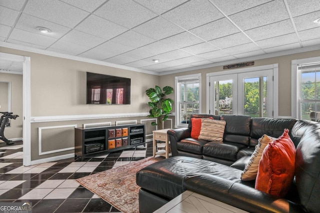 tiled living area featuring french doors, baseboards, a drop ceiling, and ornamental molding