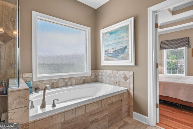 bathroom with baseboards, connected bathroom, tiled shower, and a garden tub