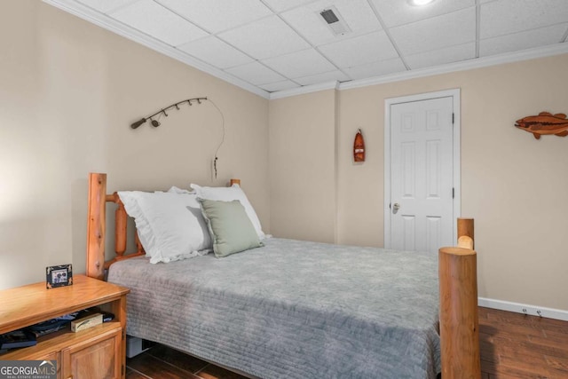 bedroom featuring visible vents, baseboards, wood finished floors, and crown molding