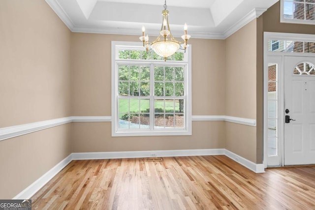 foyer featuring an inviting chandelier, a healthy amount of sunlight, and a raised ceiling