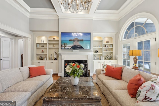 living area featuring built in features, a notable chandelier, wood finished floors, and ornamental molding