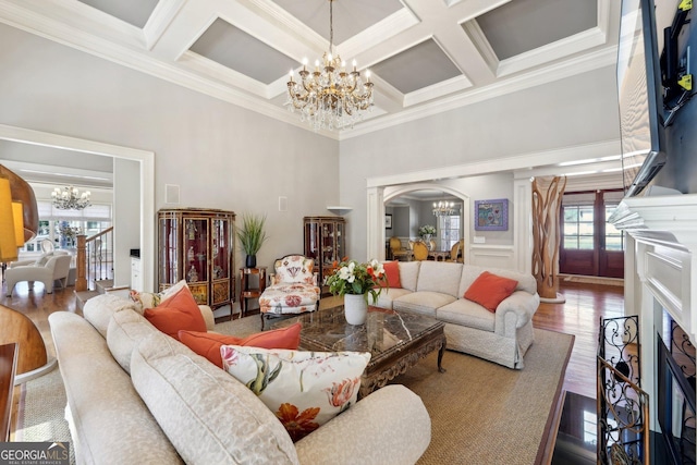 living room with beam ceiling, an inviting chandelier, wood finished floors, arched walkways, and coffered ceiling