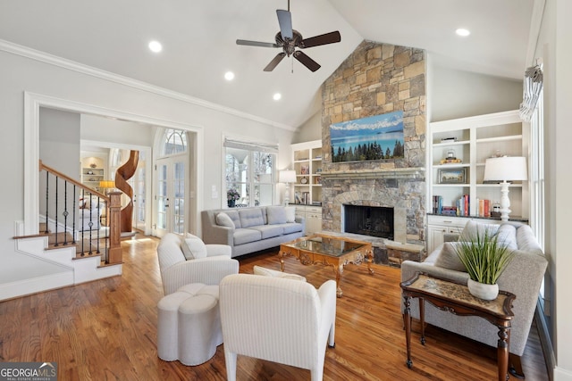 living area with wood finished floors, a fireplace, ceiling fan, stairs, and french doors