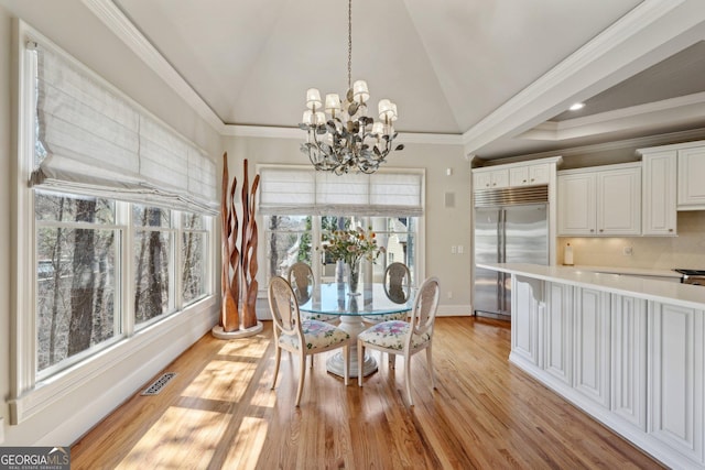 dining space with visible vents, a chandelier, vaulted ceiling, ornamental molding, and light wood-style flooring