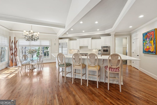 dining area featuring baseboards, light wood finished floors, ornamental molding, a raised ceiling, and a chandelier