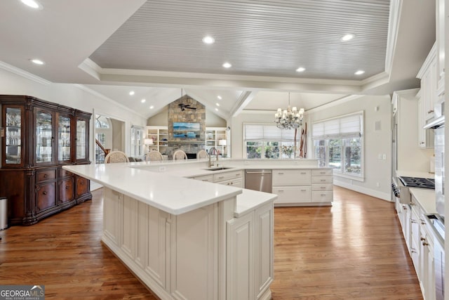 kitchen featuring light wood-style flooring, a fireplace, a sink, stainless steel dishwasher, and a chandelier