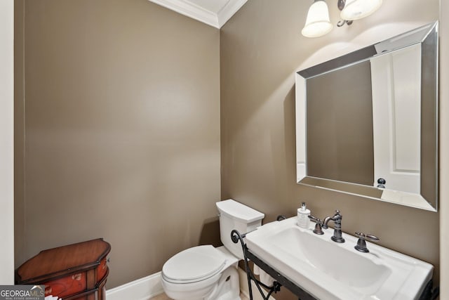 bathroom featuring crown molding, toilet, baseboards, and a sink