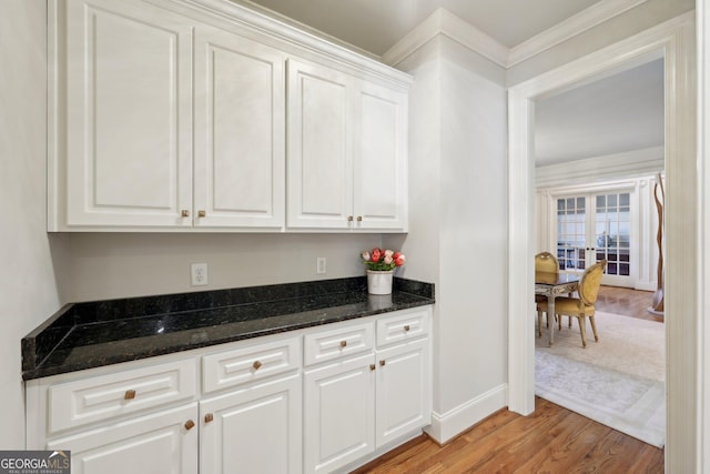 kitchen with dark stone countertops, white cabinets, baseboards, and light wood-type flooring