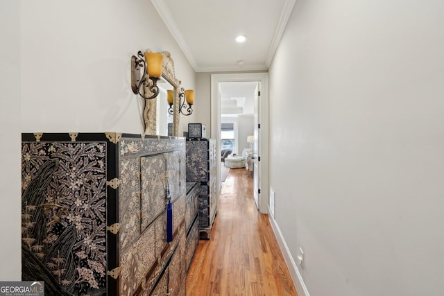 hallway with crown molding, light wood-style floors, and baseboards