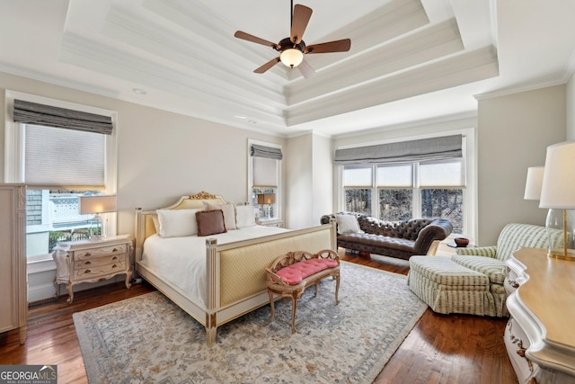 bedroom with ornamental molding, ceiling fan, a tray ceiling, and hardwood / wood-style flooring