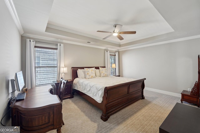 bedroom with a ceiling fan, baseboards, crown molding, a raised ceiling, and light colored carpet