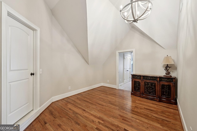 bonus room with a chandelier, vaulted ceiling, baseboards, and wood finished floors