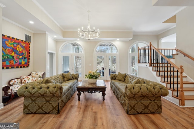 living area with stairway, wood finished floors, a chandelier, and ornamental molding