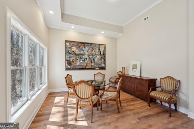 dining room with light wood finished floors, visible vents, crown molding, and baseboards