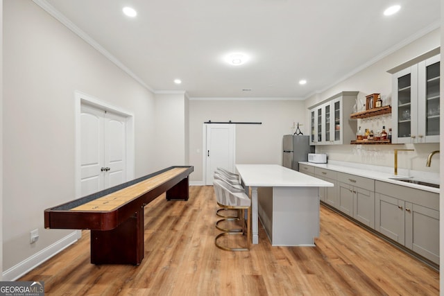 kitchen with light wood finished floors, freestanding refrigerator, a sink, gray cabinetry, and a barn door