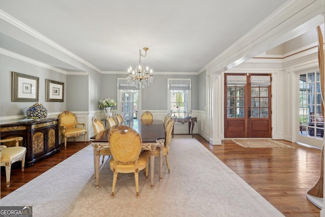 dining space featuring plenty of natural light, a wainscoted wall, and a chandelier