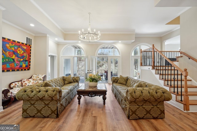 living area with wood finished floors, recessed lighting, an inviting chandelier, crown molding, and stairs