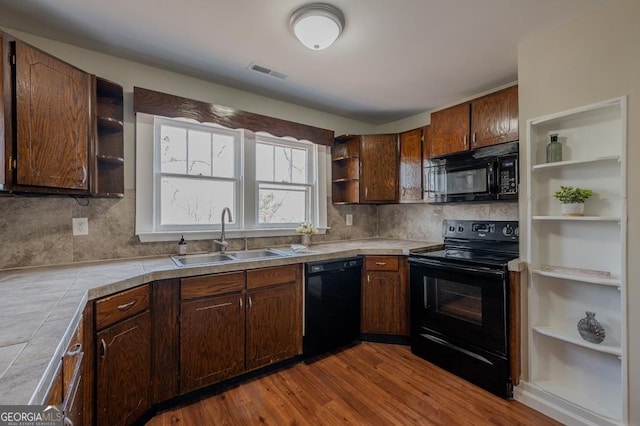 kitchen featuring visible vents, black appliances, open shelves, a sink, and tile counters