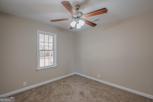 carpeted empty room featuring visible vents, a ceiling fan, and baseboards