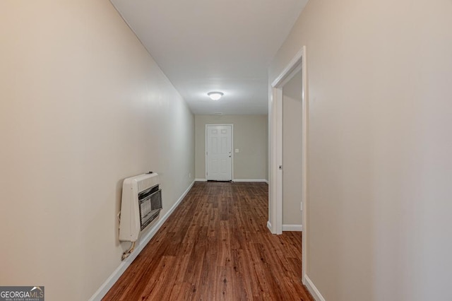 hall featuring heating unit, baseboards, and wood finished floors