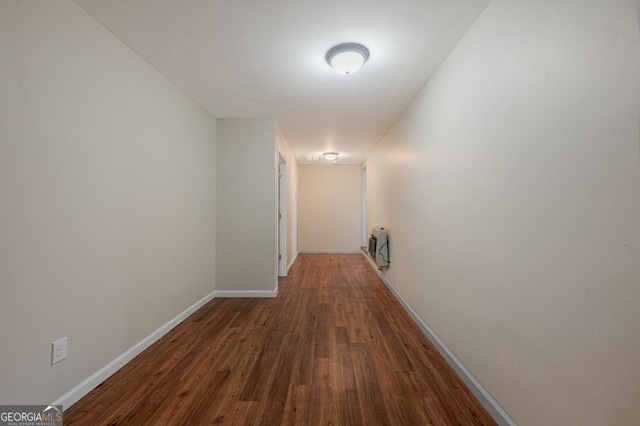 corridor featuring heating unit, wood finished floors, and baseboards