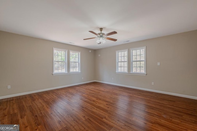 empty room with baseboards, dark wood-type flooring, and a ceiling fan