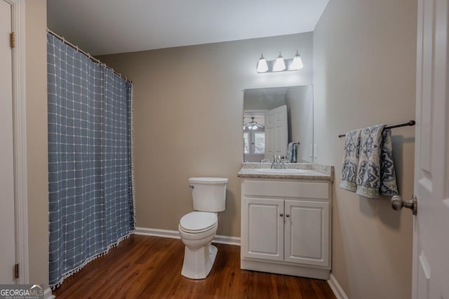 full bathroom with vanity, a shower with curtain, wood finished floors, baseboards, and toilet