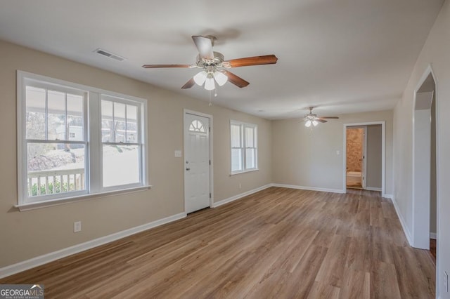 unfurnished living room with light wood-type flooring, baseboards, visible vents, and ceiling fan