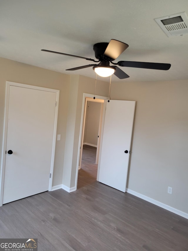 unfurnished bedroom with a ceiling fan, wood finished floors, visible vents, and baseboards