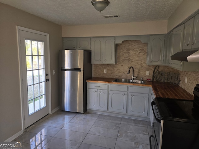 kitchen featuring visible vents, wooden counters, under cabinet range hood, appliances with stainless steel finishes, and a sink