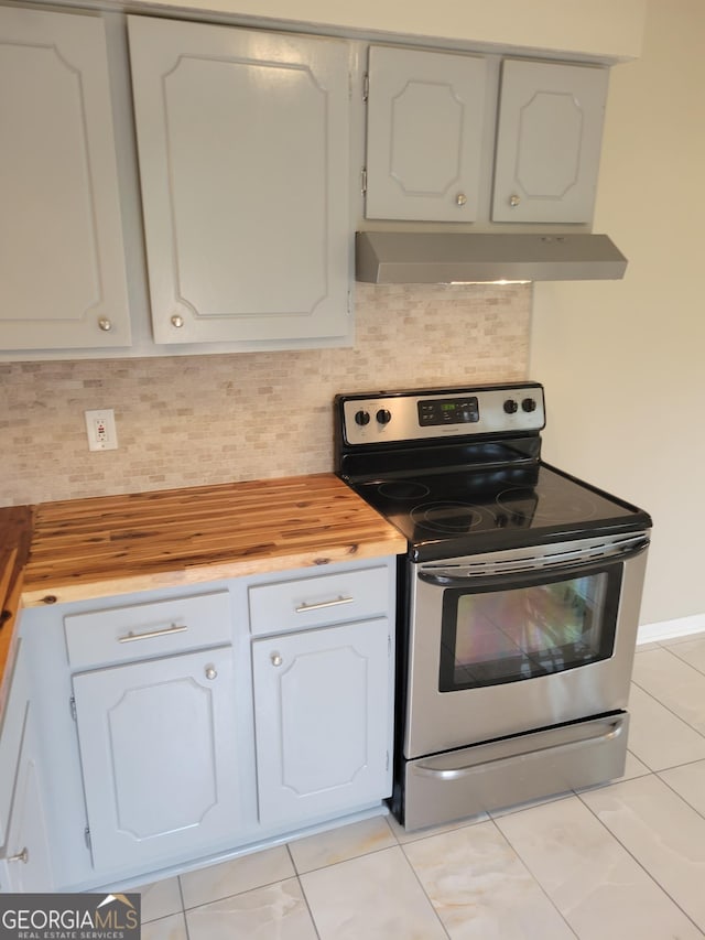 kitchen featuring electric range, under cabinet range hood, white cabinetry, backsplash, and butcher block counters