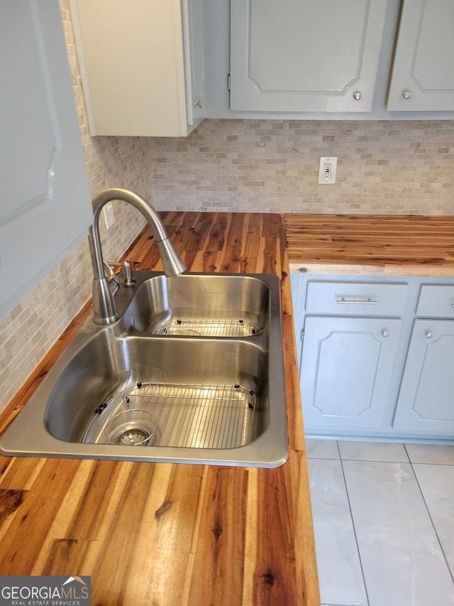 kitchen featuring a sink, decorative backsplash, butcher block countertops, and white cabinets