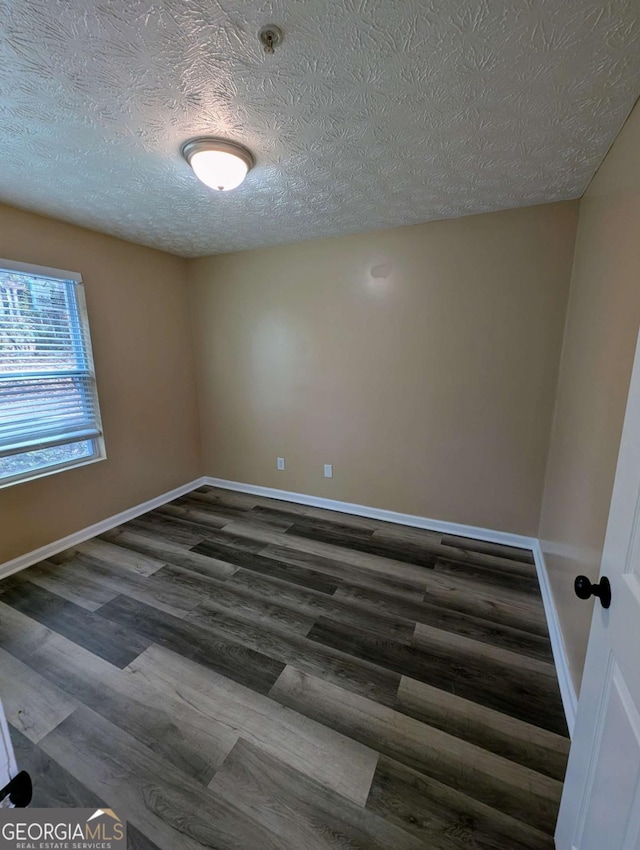unfurnished room with baseboards, a textured ceiling, and dark wood-style floors