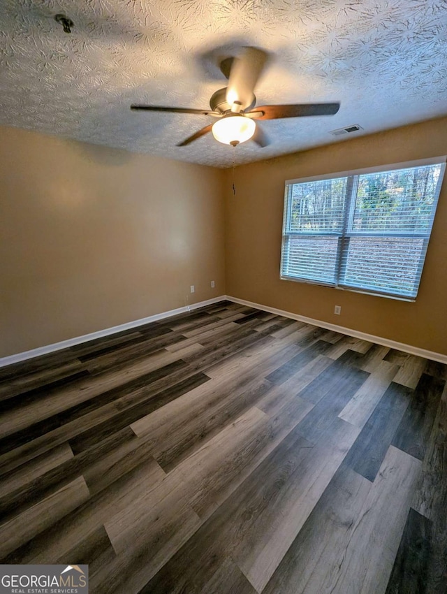 unfurnished room featuring visible vents, baseboards, a ceiling fan, and dark wood-style flooring