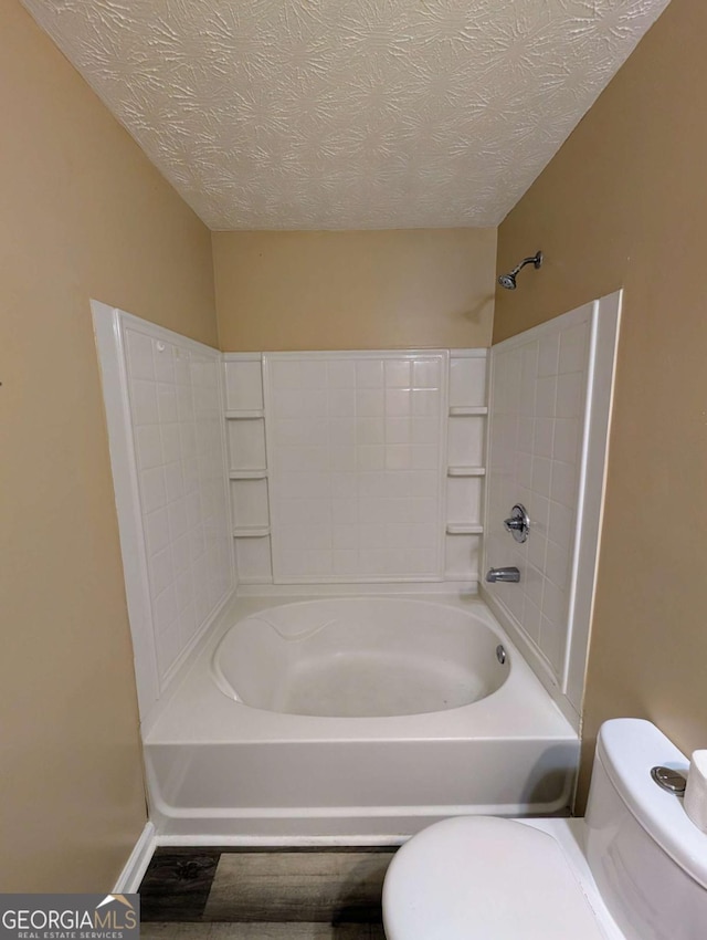 full bathroom featuring toilet, tub / shower combination, and a textured ceiling
