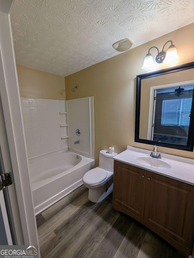 full bathroom featuring toilet, a textured ceiling, wood finished floors, shower / bath combination, and vanity