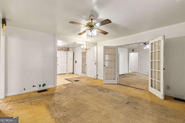 spare room featuring french doors, ceiling fan with notable chandelier, visible vents, and carpet floors