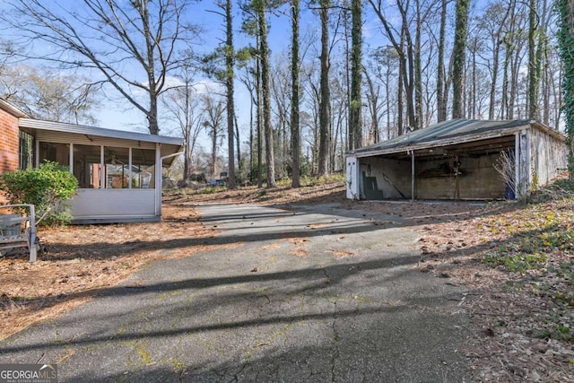 exterior space featuring driveway, an outdoor structure, and a sunroom