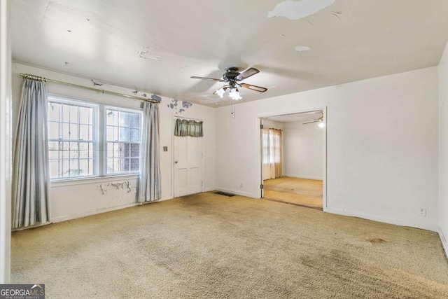 carpeted empty room with a ceiling fan, visible vents, and baseboards