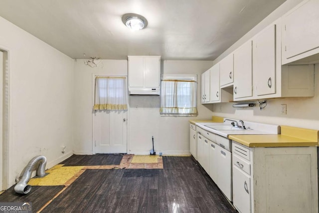 kitchen featuring under cabinet range hood, light countertops, dark wood-style floors, white cabinets, and a sink